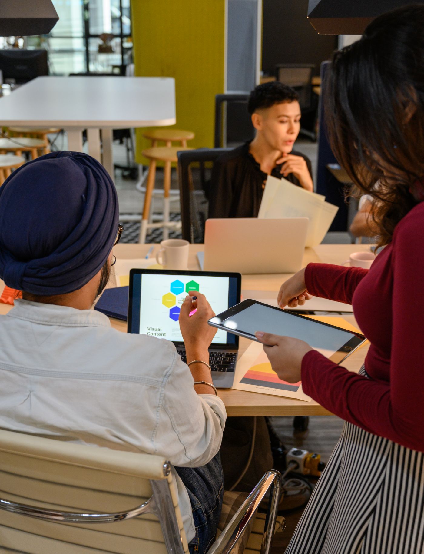Young professionals discussing a project with laptops and tablets