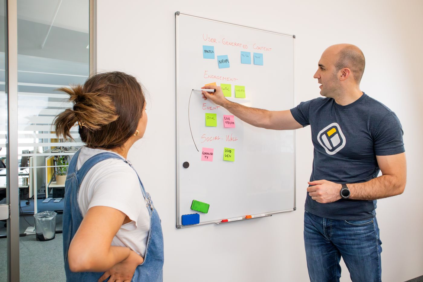 Two colleagues brainstorming strategy on a whiteboard